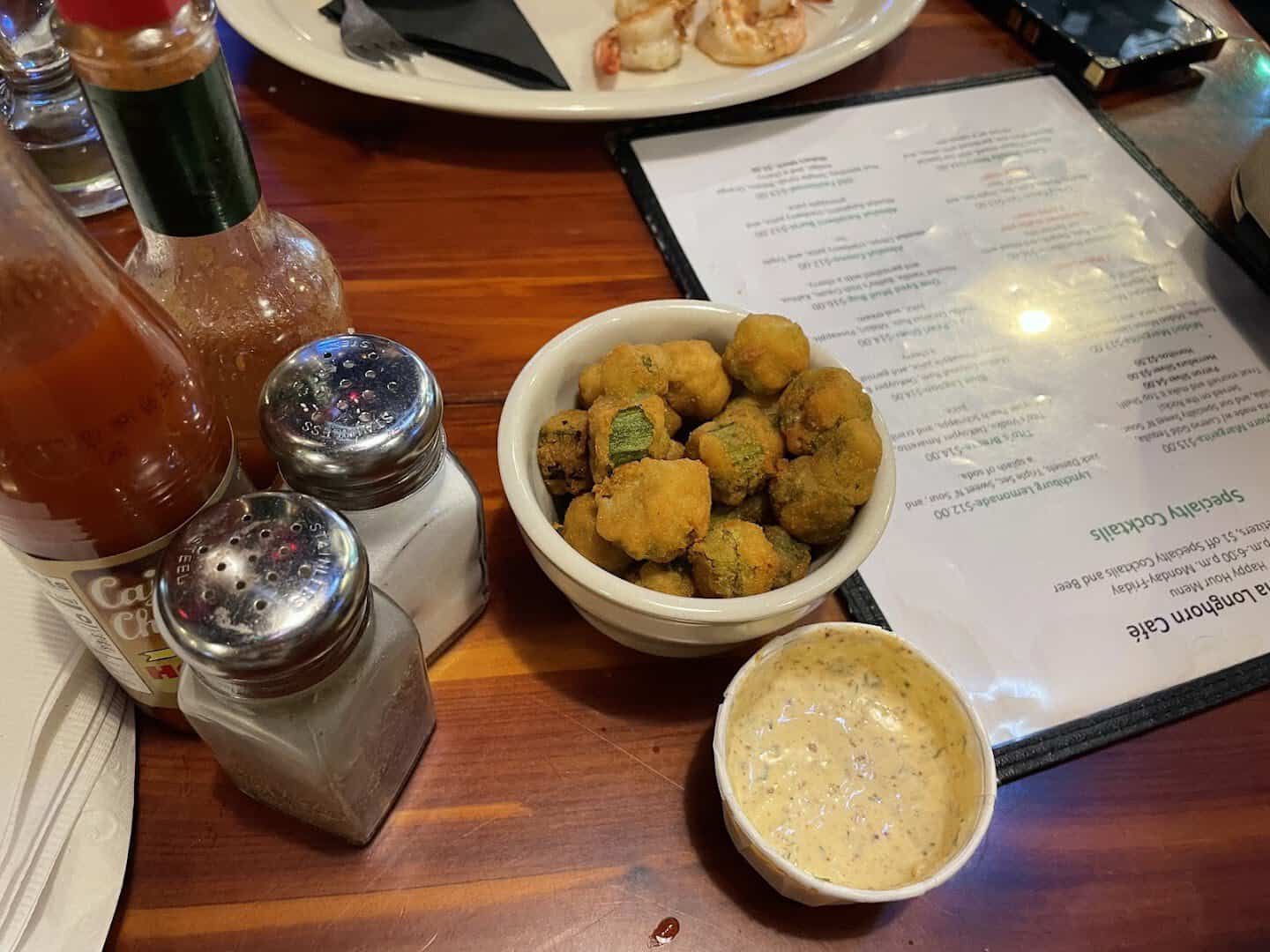 Fried okra with a cup of remoulade beside the menu at Louisiana Longhorn Cafe in Round Rock, Texas