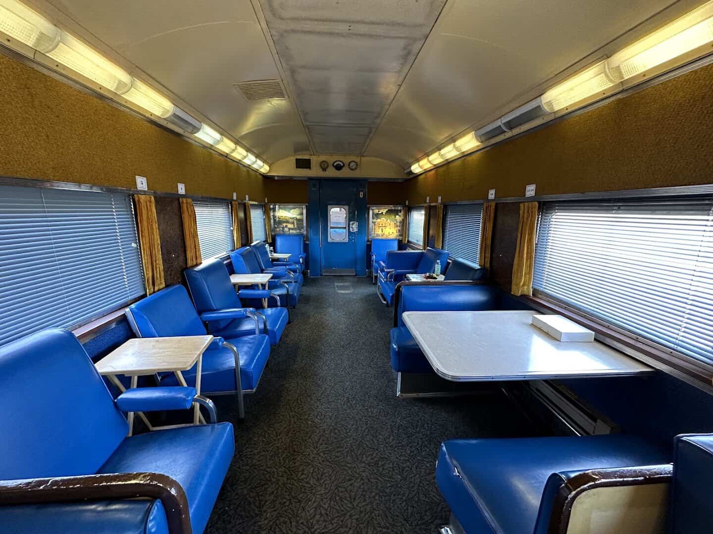 Interior of a restored lounge car with blue booth seating on the Hill Country Flyer