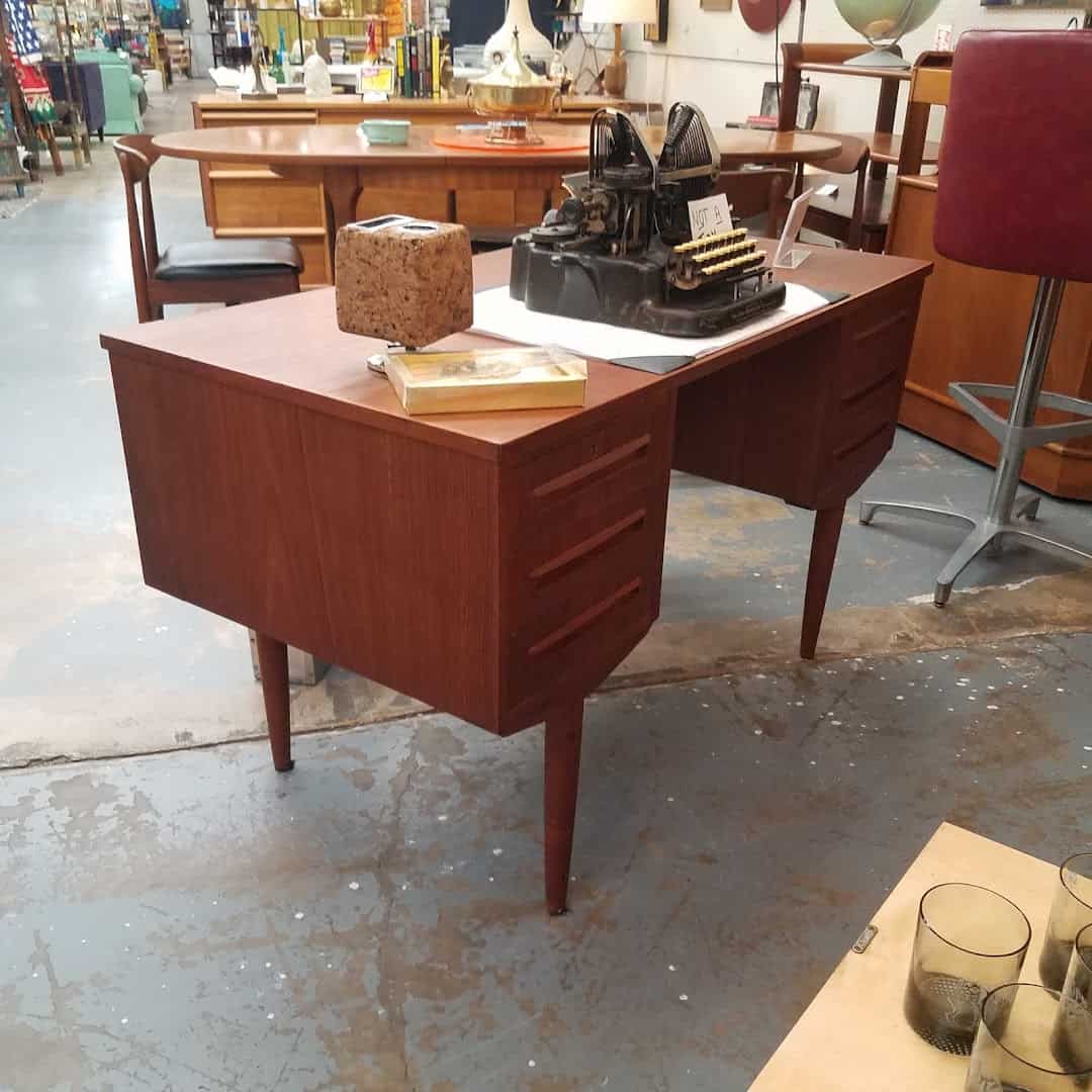 A mid-century teak desk with a vintage typewriter at Lula B's Design District in Dallas