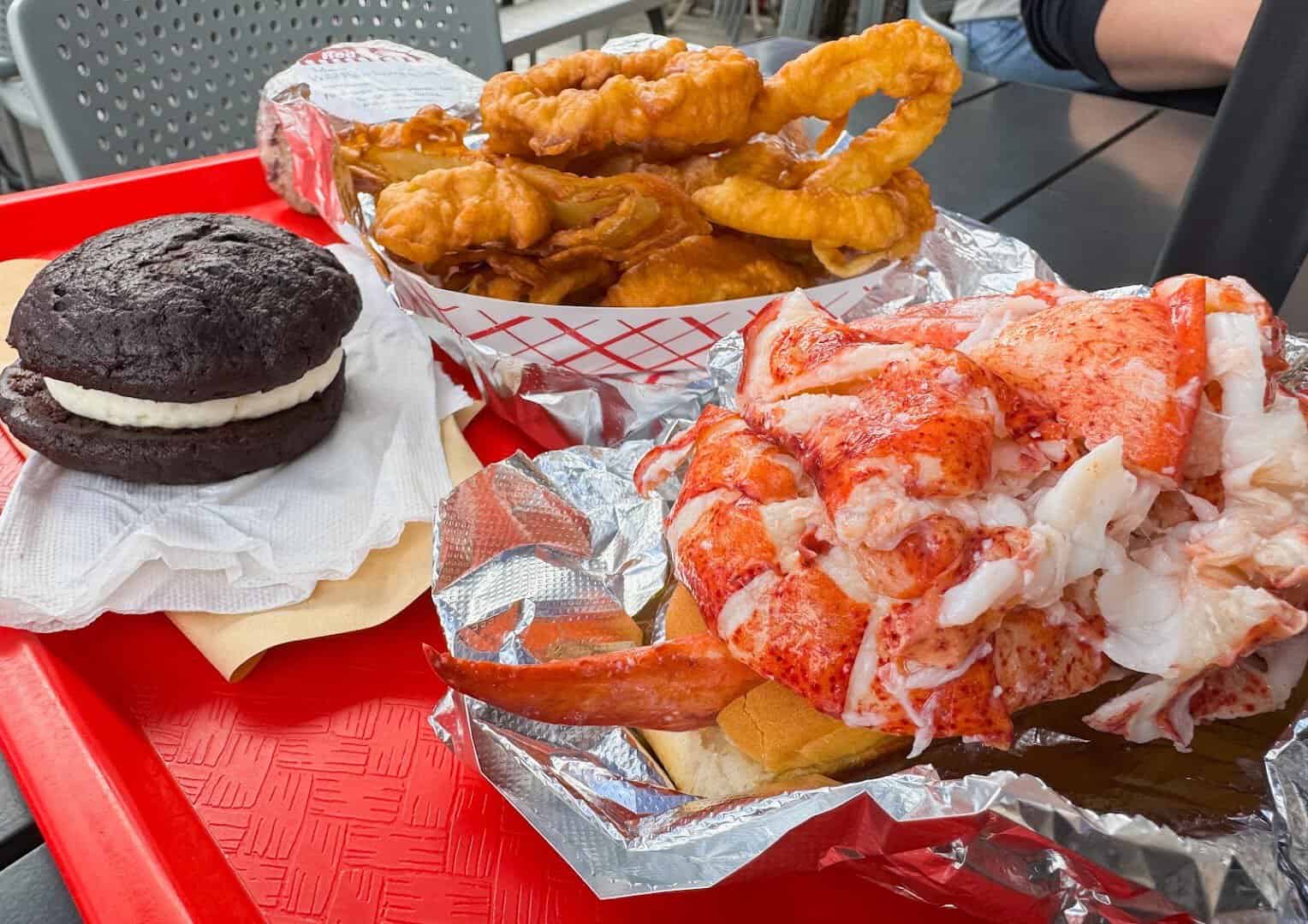 Lobster roll overflowing with lobster meat, fried seafood and whoopie pie on a Maine tray