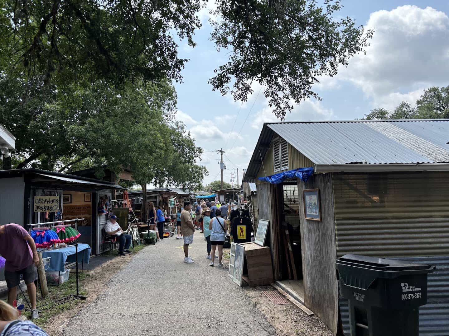 Shoppers browsing a lane of booths under the oaks at Wimberley Market Days