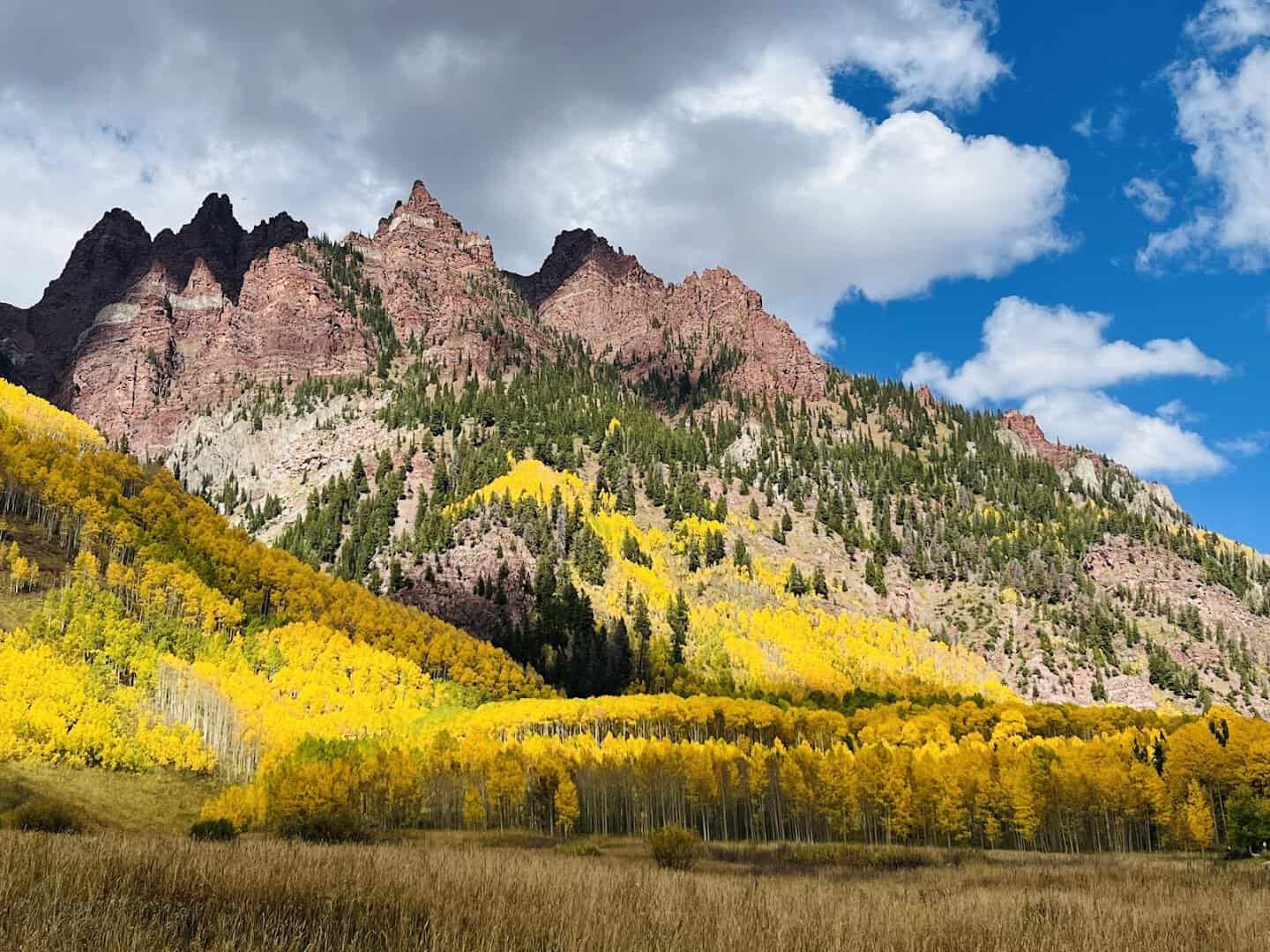 Maroon Bells peaks above a meadow of golden autumn aspens near Aspen, Colorado