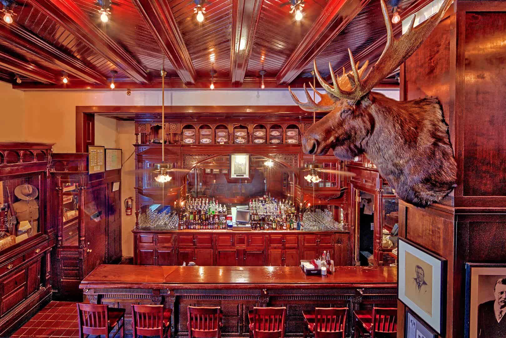The historic Menger Bar with carved dark wood and a mounted moose head at the Menger Hotel in San Antonio, Texas