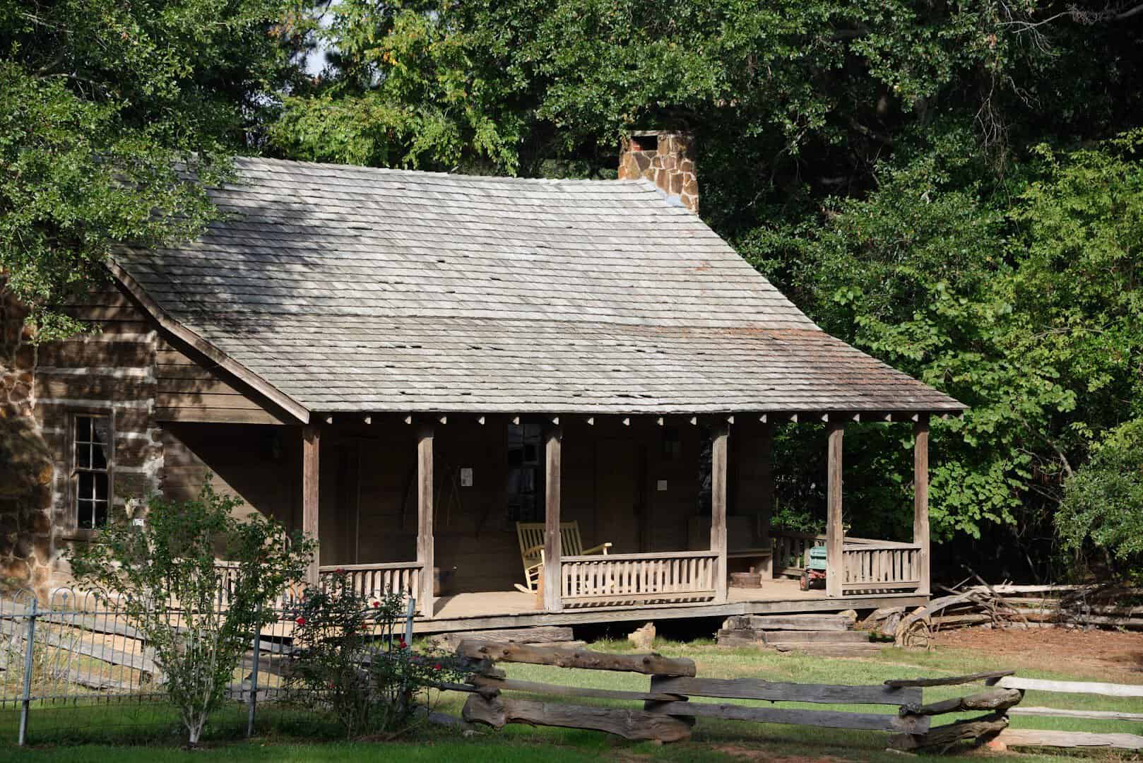 Historic log cabin with a porch at Millard's Crossing Historic Village in Nacogdoches, Texas