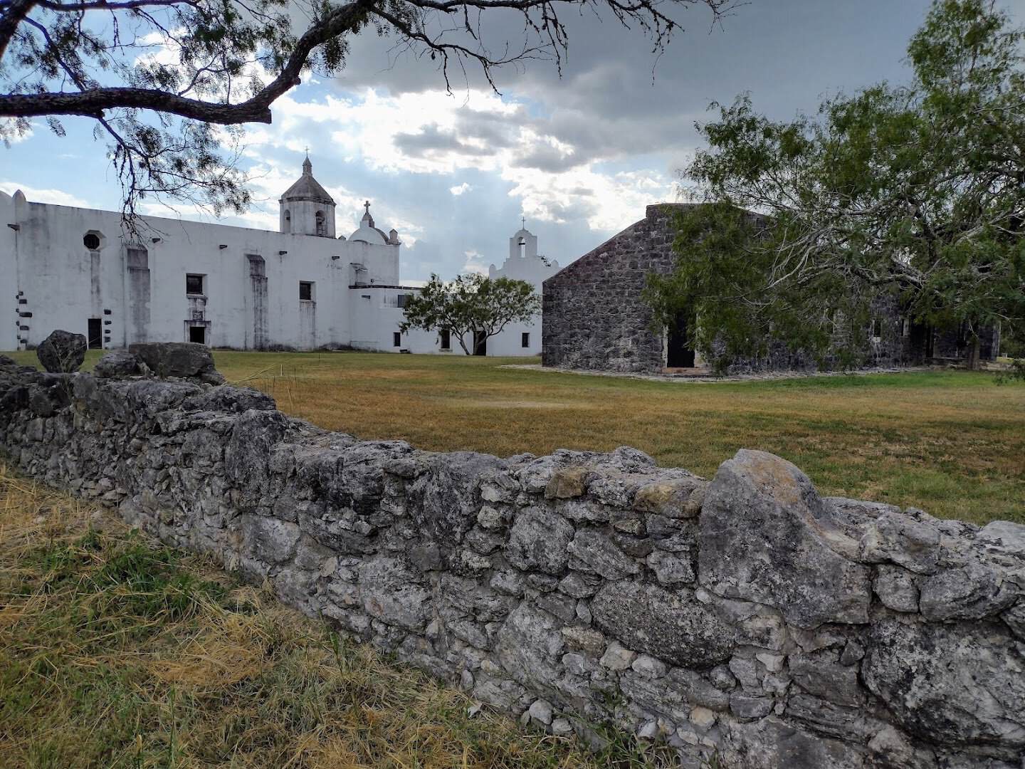 Mission Espiritu Santo church and stone granary behind a rock wall at Goliad State Park, Texas