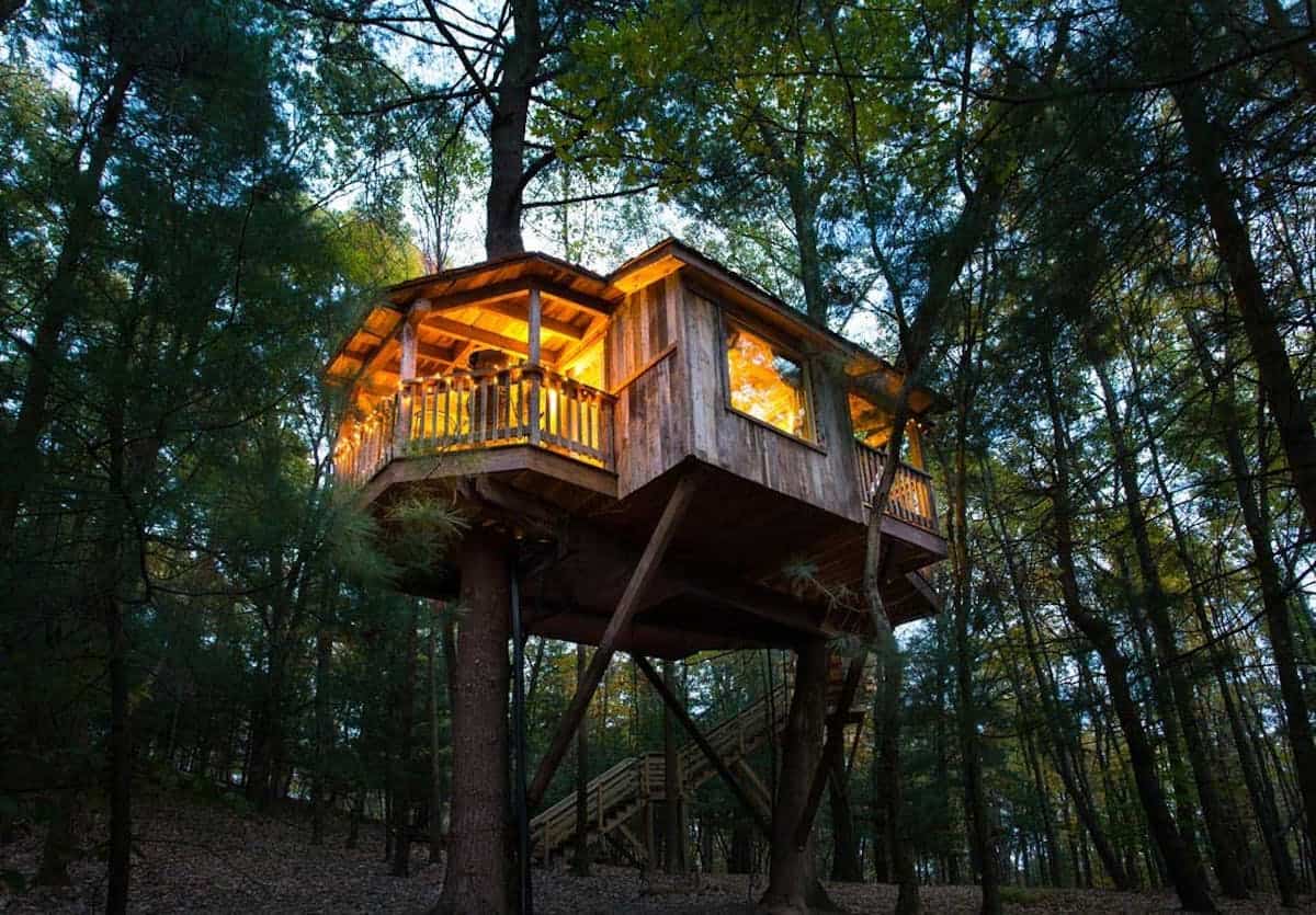 Treehouse glowing among the trees at The Mohicans Treehouse Resort in Ohio