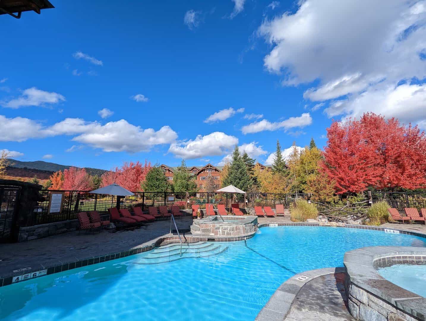 The Whiteface Lodge with a spa pool framed by fall foliage in Lake Placid, New York