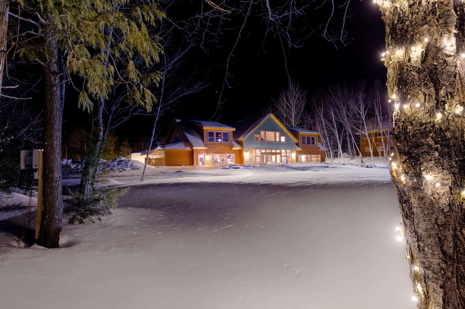 Cabins lit in the snow at night at New England Outdoor Center in Millinocket, Maine