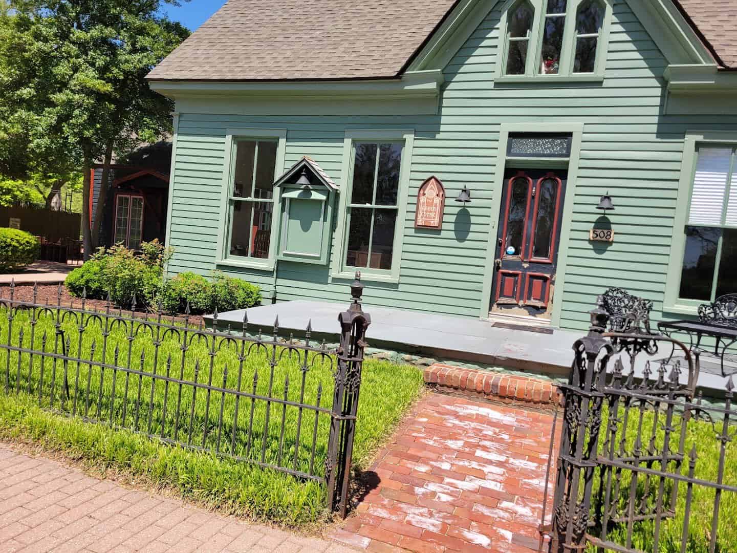 Green Victorian house with iron fence in New Harmony, Indiana
