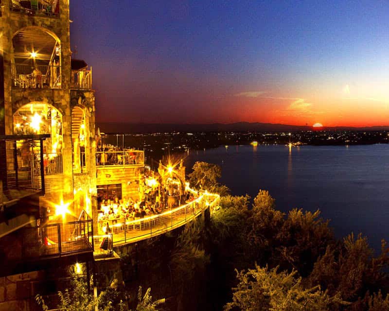 The Oasis on Lake Travis decks lit golden at sunset over the lake in Austin