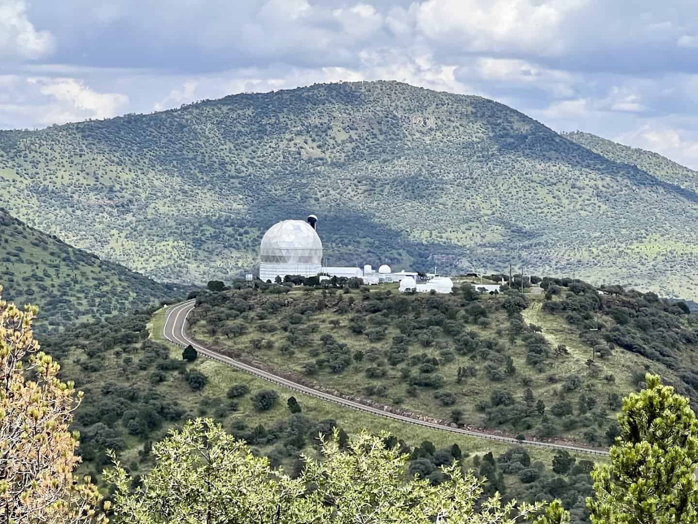 A white observatory dome on a green ridge in the Davis Mountains at McDonald Observatory, Texas