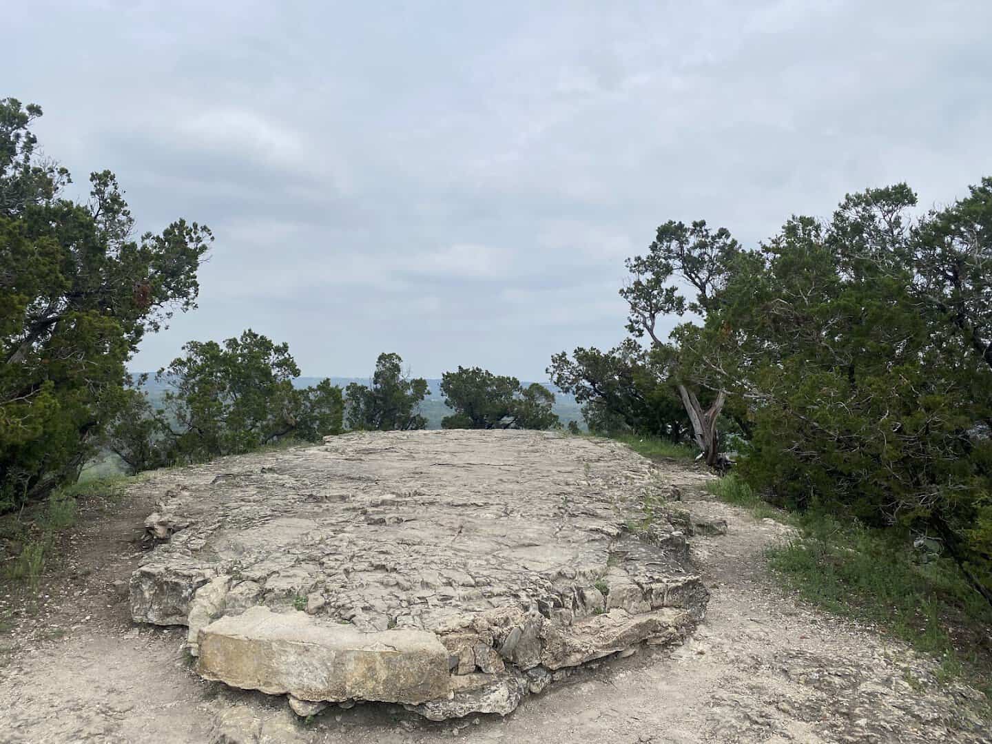 The flat rocky summit clearing of Old Baldy ringed by cedar and oak