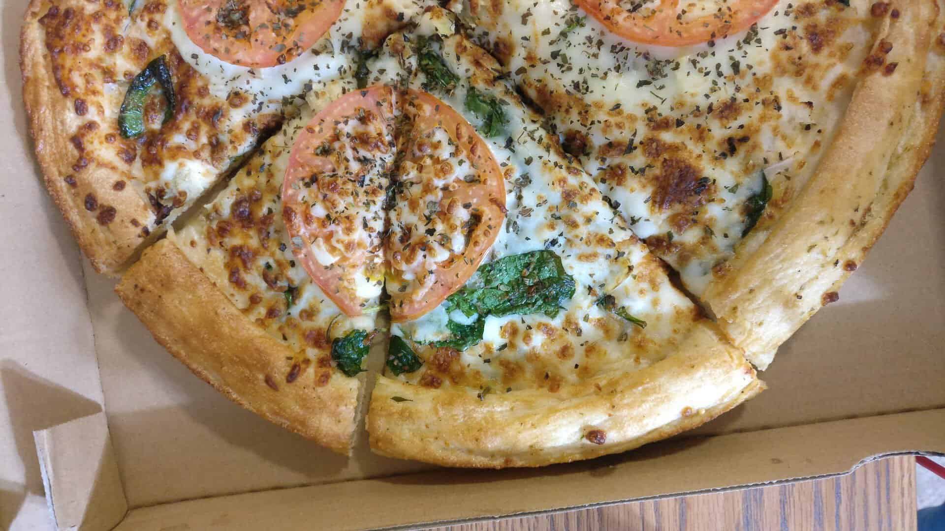 A white pizza topped with tomato and basil at Old School Pizza Tavern in Arlington, Texas