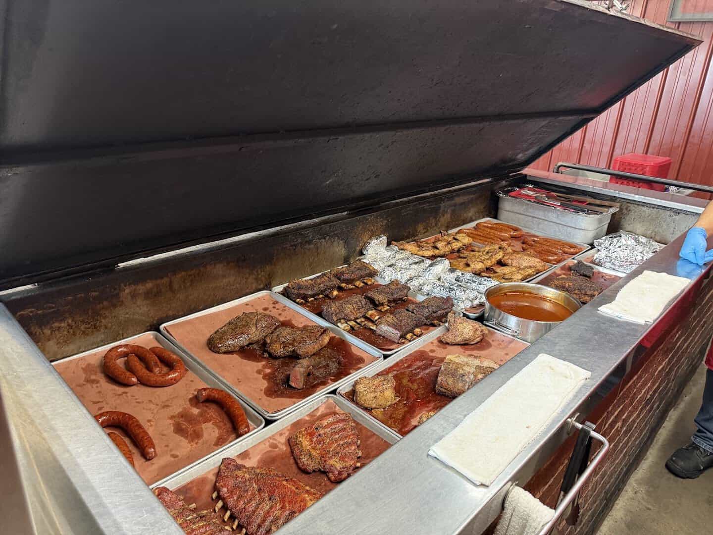 Open brick pit full of smoked meats at Cooper's Old Time Pit Bar-B-Que in Fort Worth