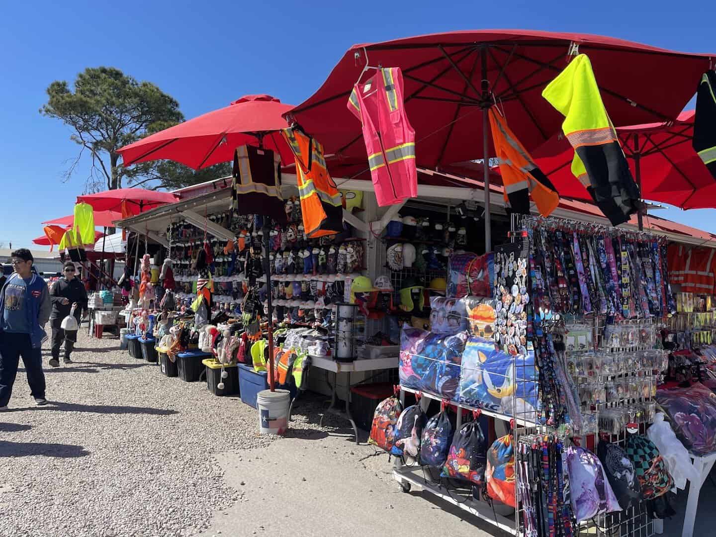 Outdoor stalls under red umbrellas with hanging merchandise at Cole's flea market in Pearland, Texas