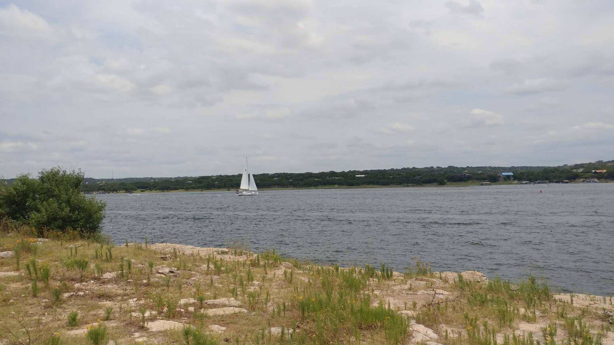 Sailboat on Lake Travis seen from the limestone shore of Pace Bend Park