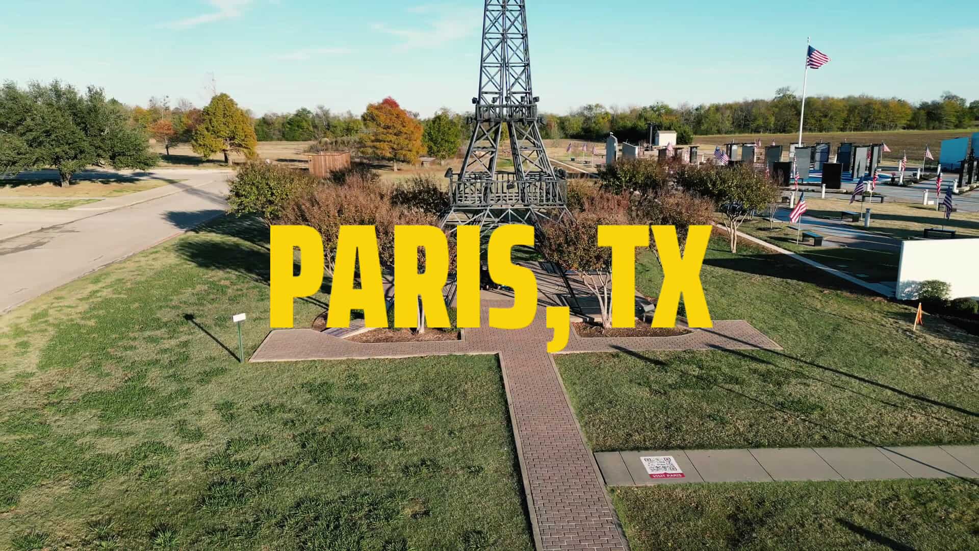 The Paris, Texas Eiffel Tower rising behind a Paris TX sign