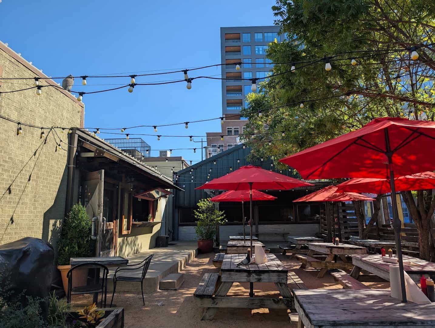 The back patio with string lights and red umbrellas at Pecan Lodge in Dallas