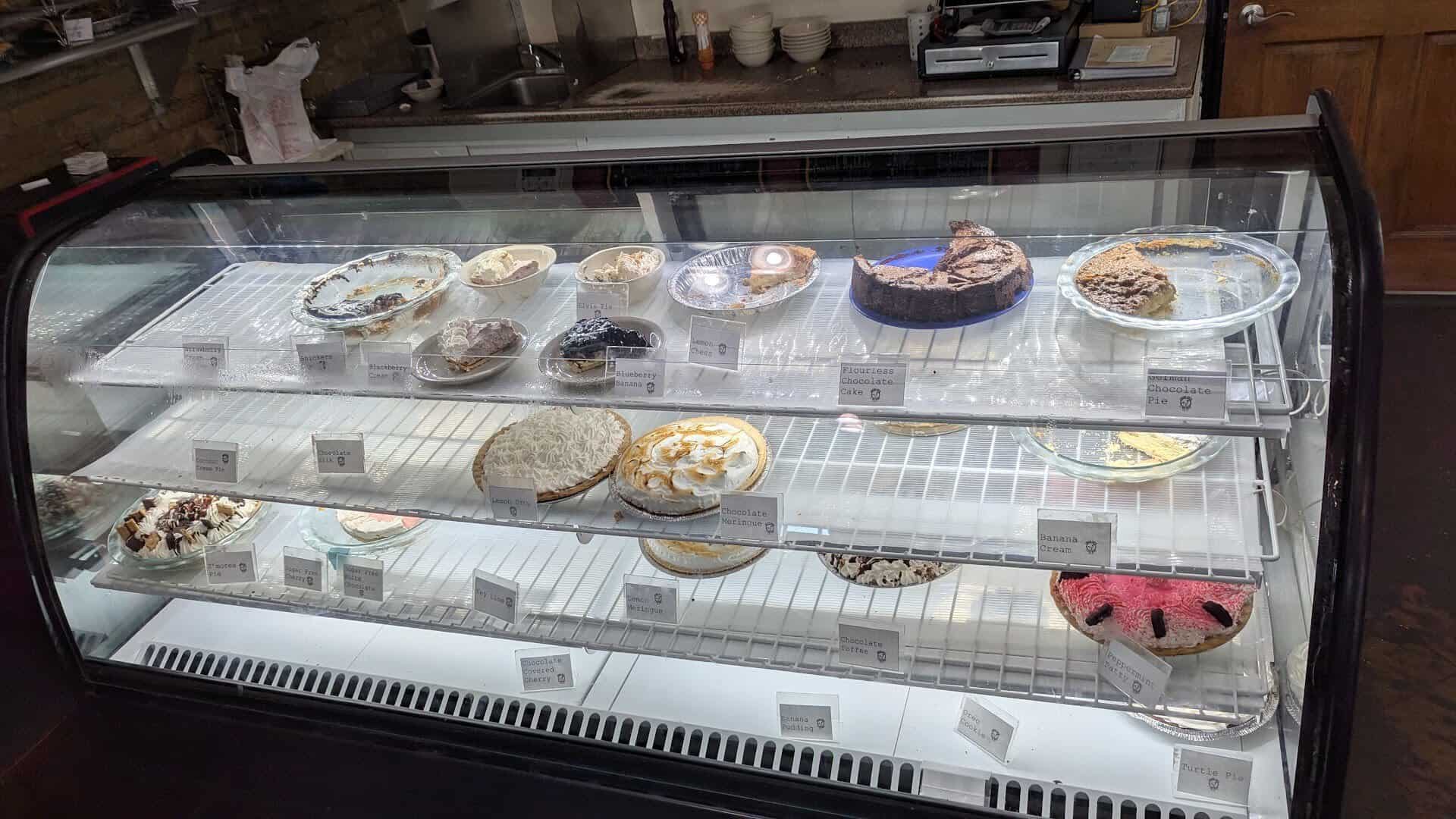 Glass display case filled with whole cream pies at Texan Cafe and Pie Shop in Hutto, Texas