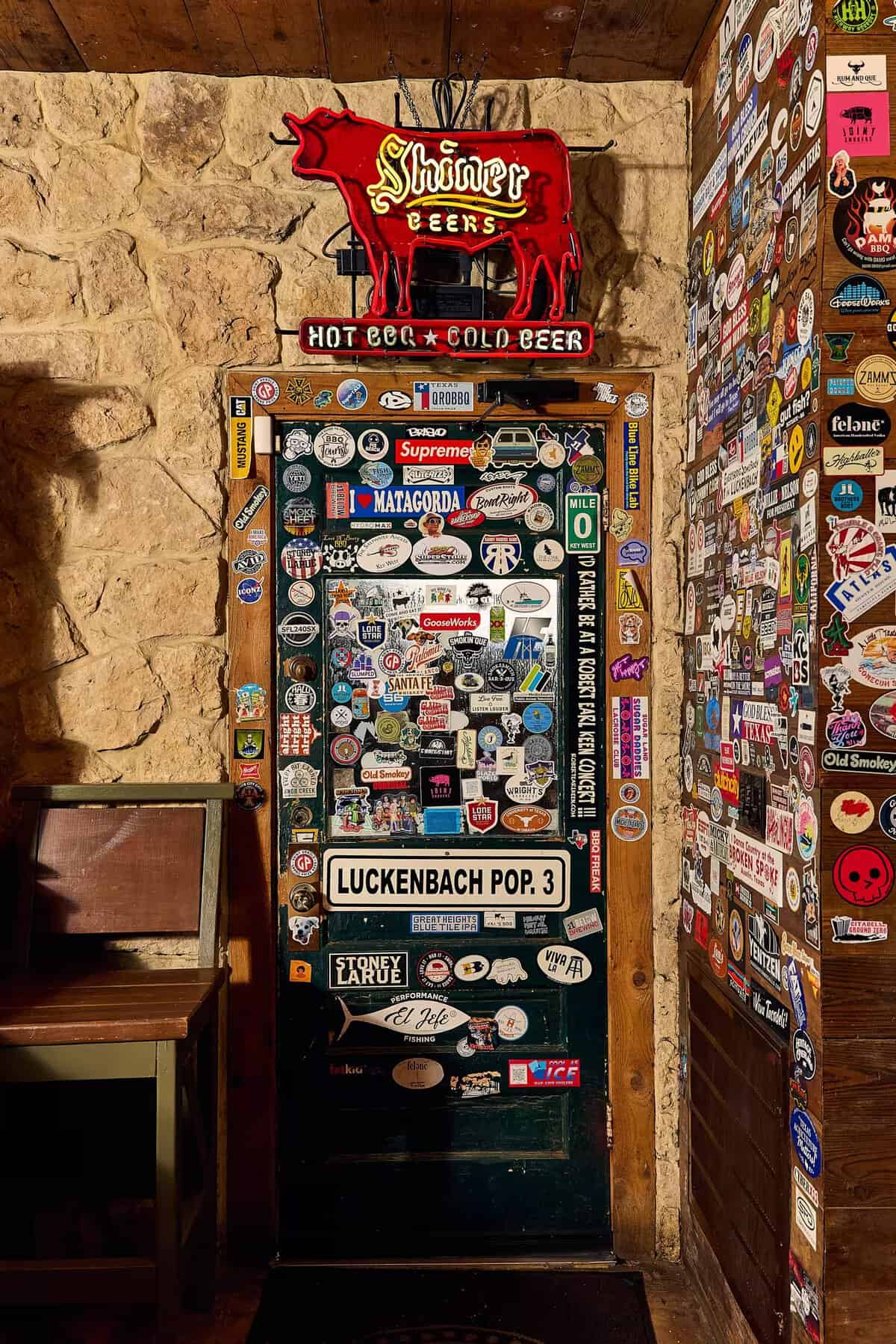 Shiner neon sign and sticker-covered door inside Pinkerton's Barbecue