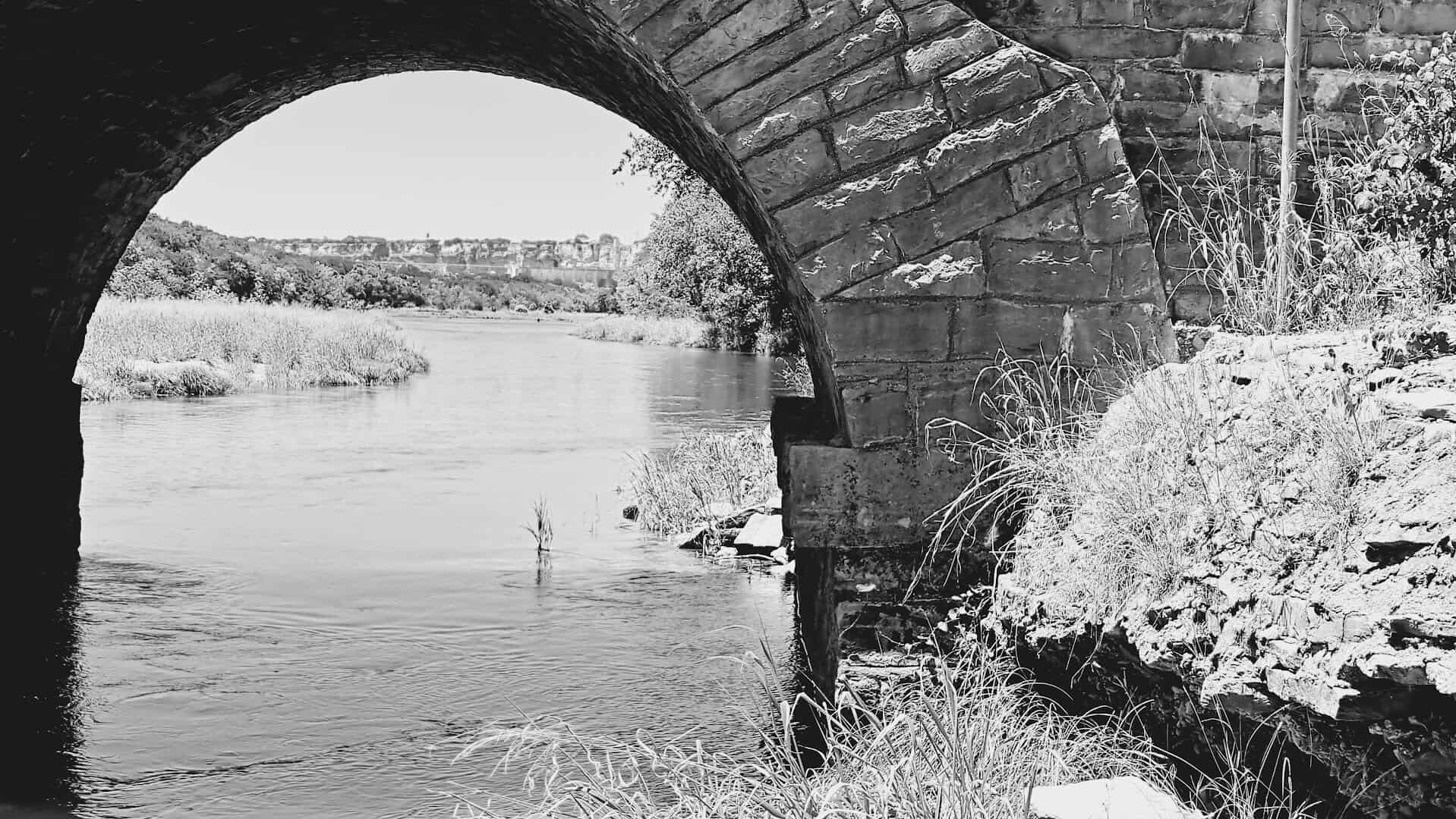 Black and white view through a stone arch of the historic Possum Kingdom Stone Arch Bridge