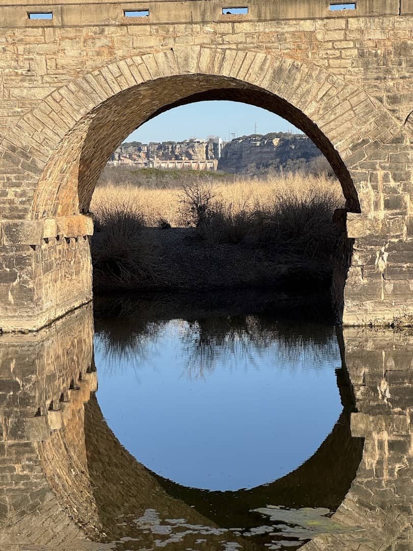 The Brazos River reflected through a stone arch of the Possum Kingdom Stone Arch Bridge