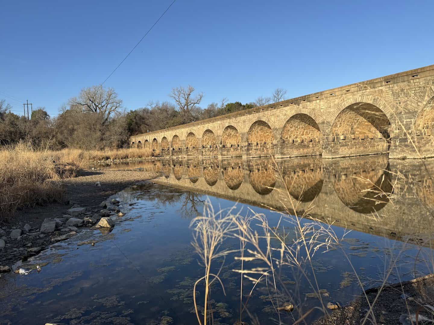 The Possum Kingdom Stone Arch Bridge reflected in the calm Brazos River at golden hour