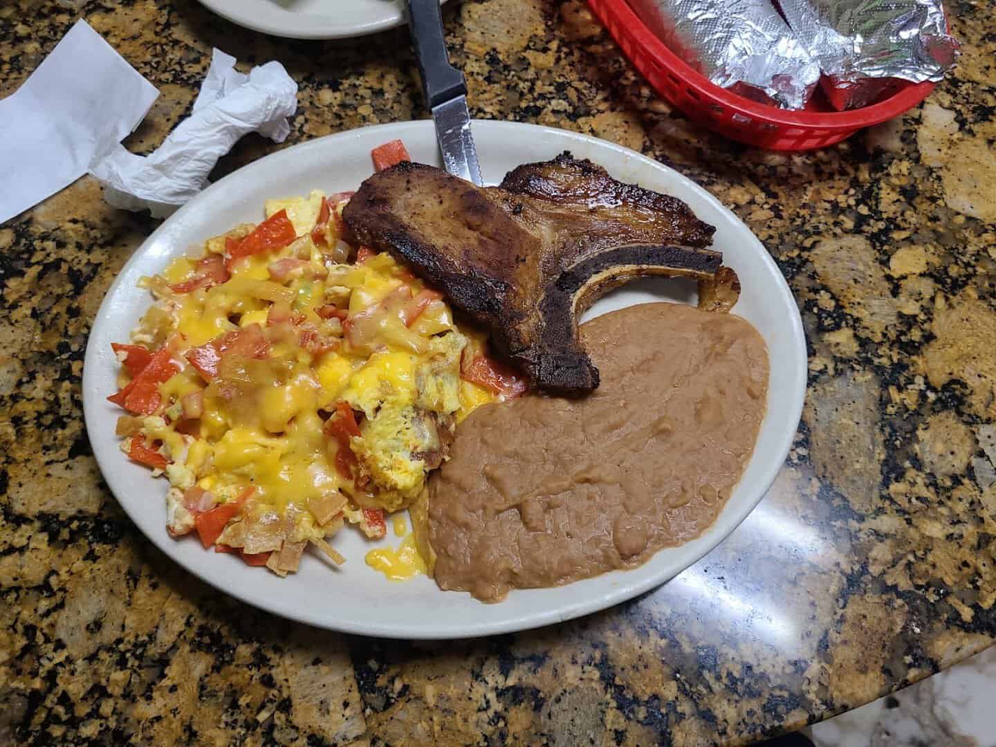 Pork chop and migas plate with refried beans at Eddie's Taco House