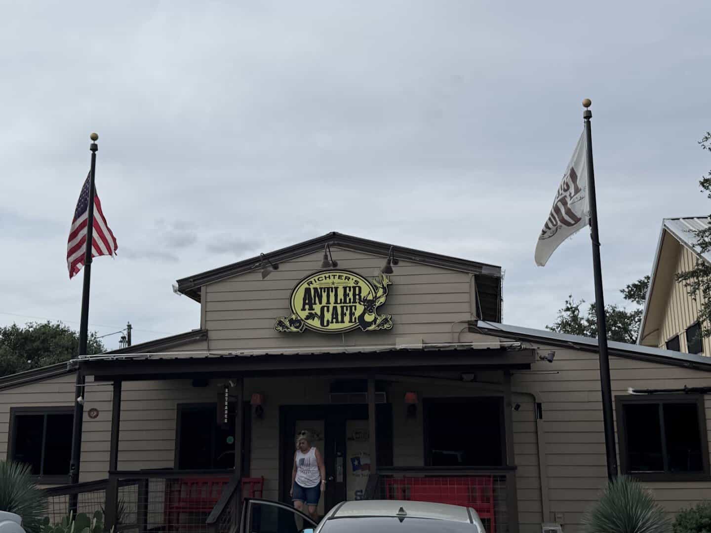 Exterior of Richter's Antler Cafe with its deer logo sign and flags in Spring Branch, Texas