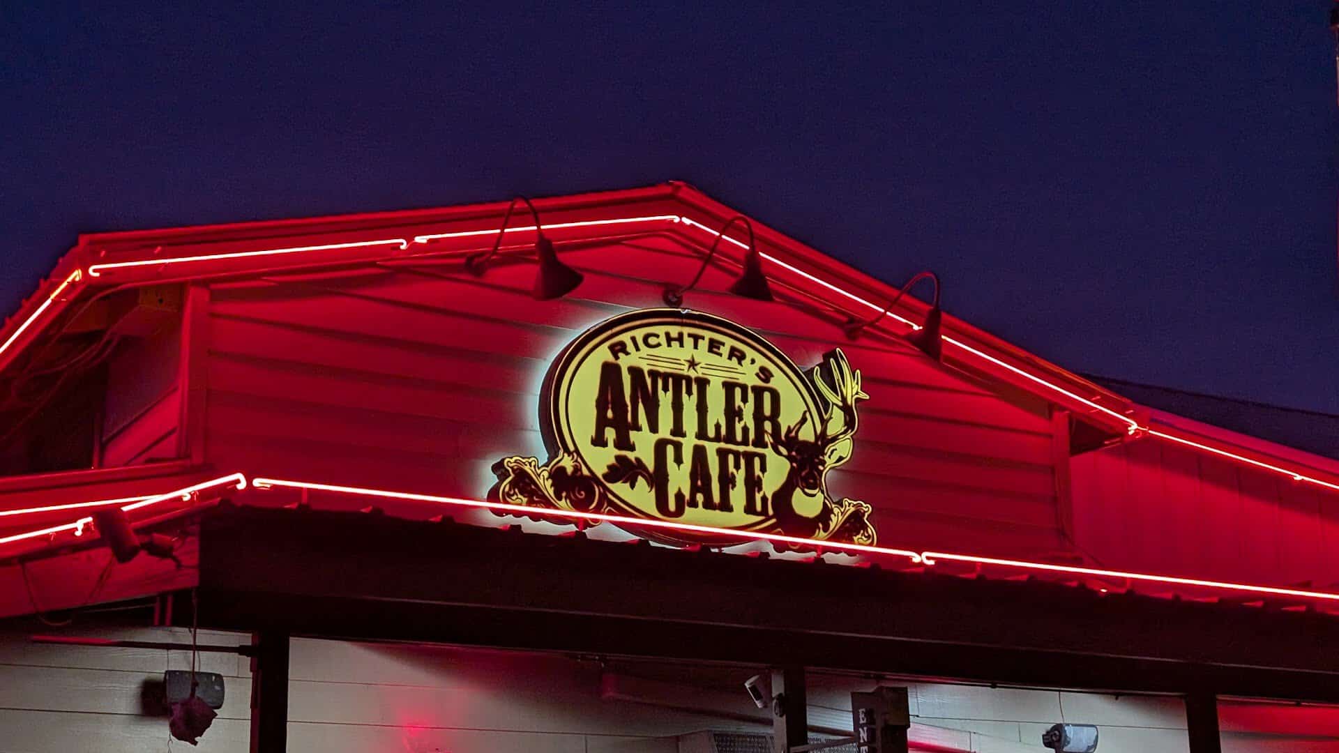 Richter's Antler Cafe neon sign glowing red above the roofline at night in Spring Branch, Texas