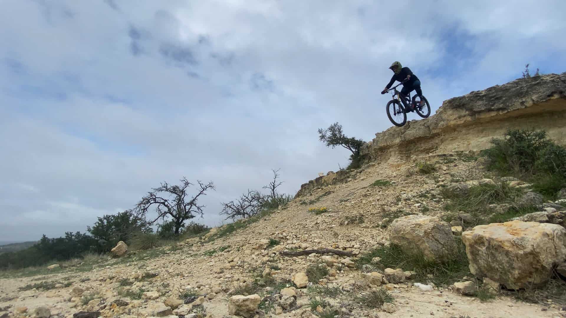 Rider descending a steep rocky trail at Flat Rock Ranch near Comfort, Texas