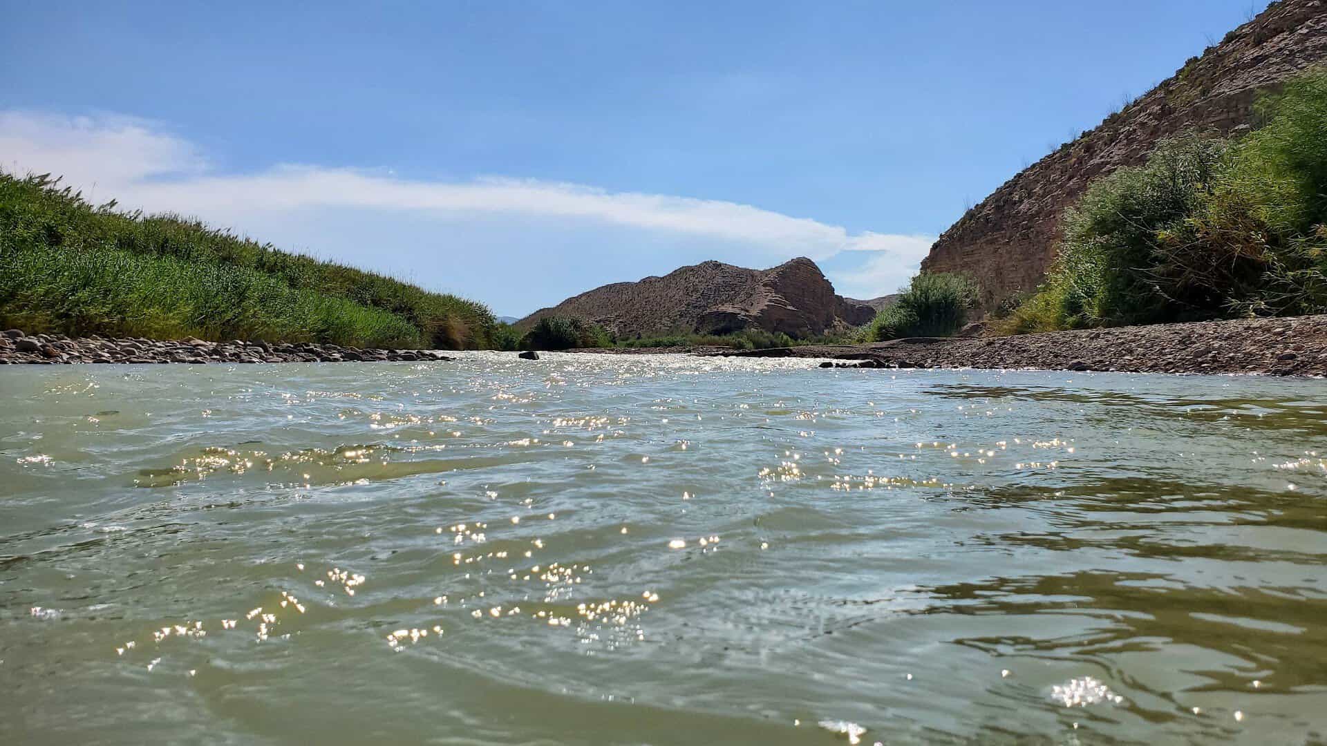 The Rio Grande flowing between reeds and desert hills at Big Bend National Park