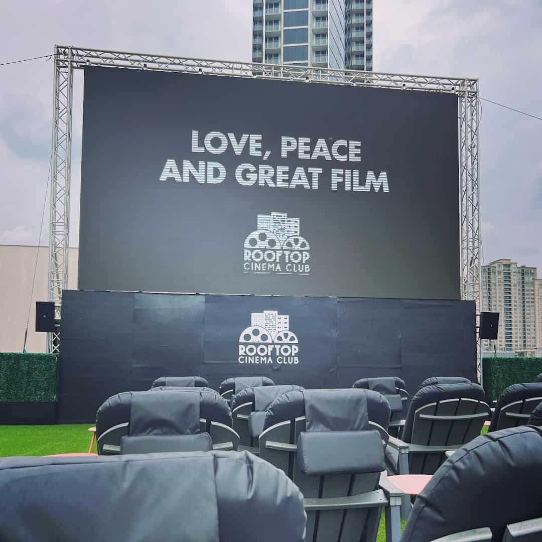 Outdoor cinema screen reading Love Peace and Great Film with the Houston skyline at Rooftop Cinema Club Uptown
