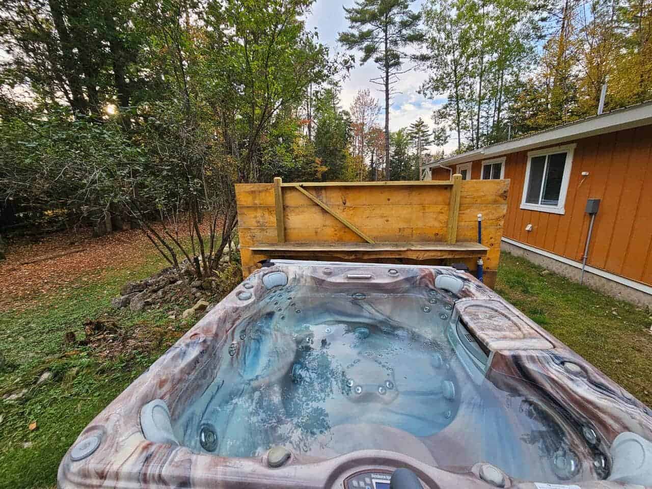 Private hot tub beside a log cabin in fall at Rustic Log Cabins in the White Mountains, New Hampshire