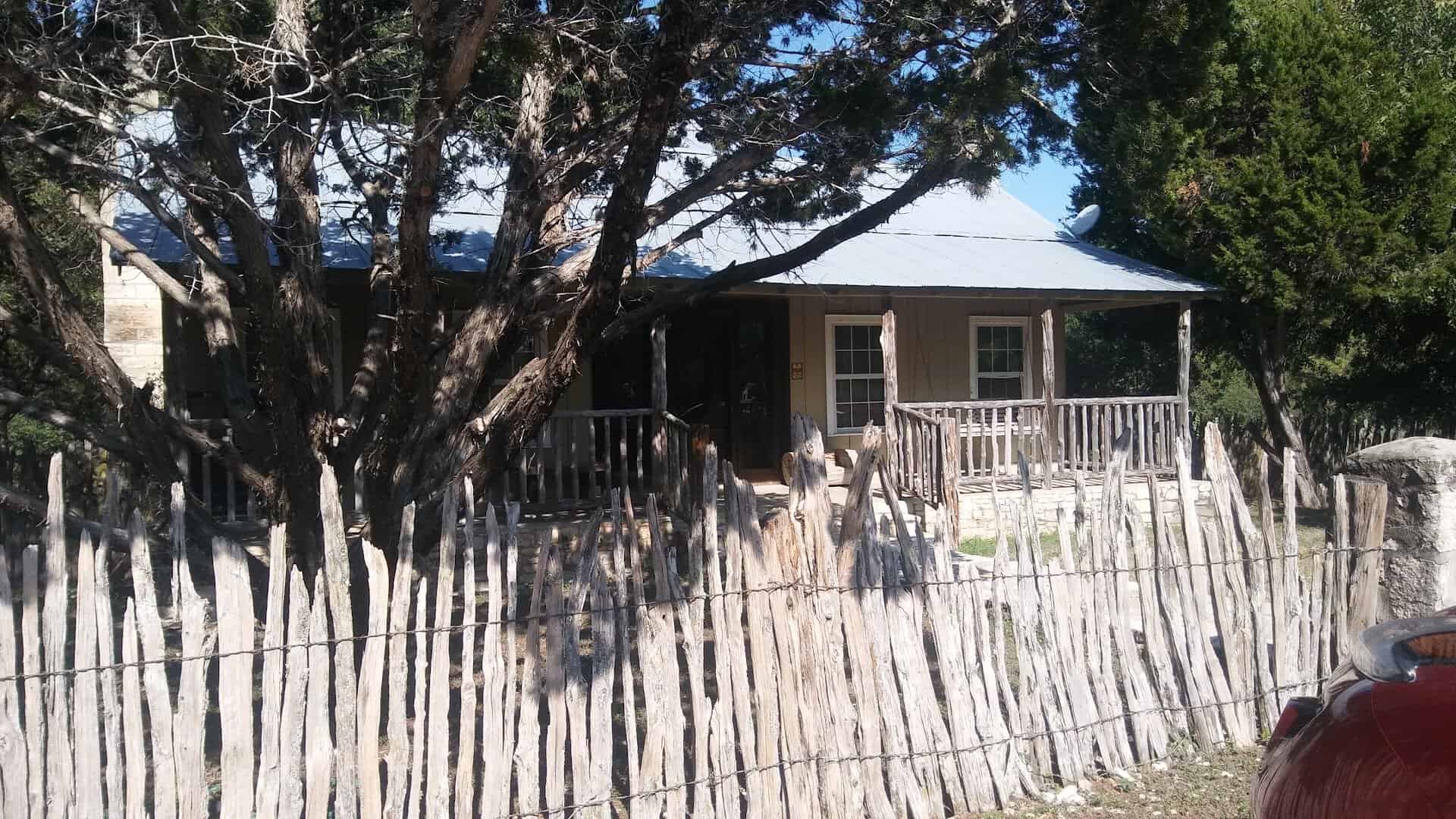 A rustic cabin behind a cedar-post fence in Concan, Texas