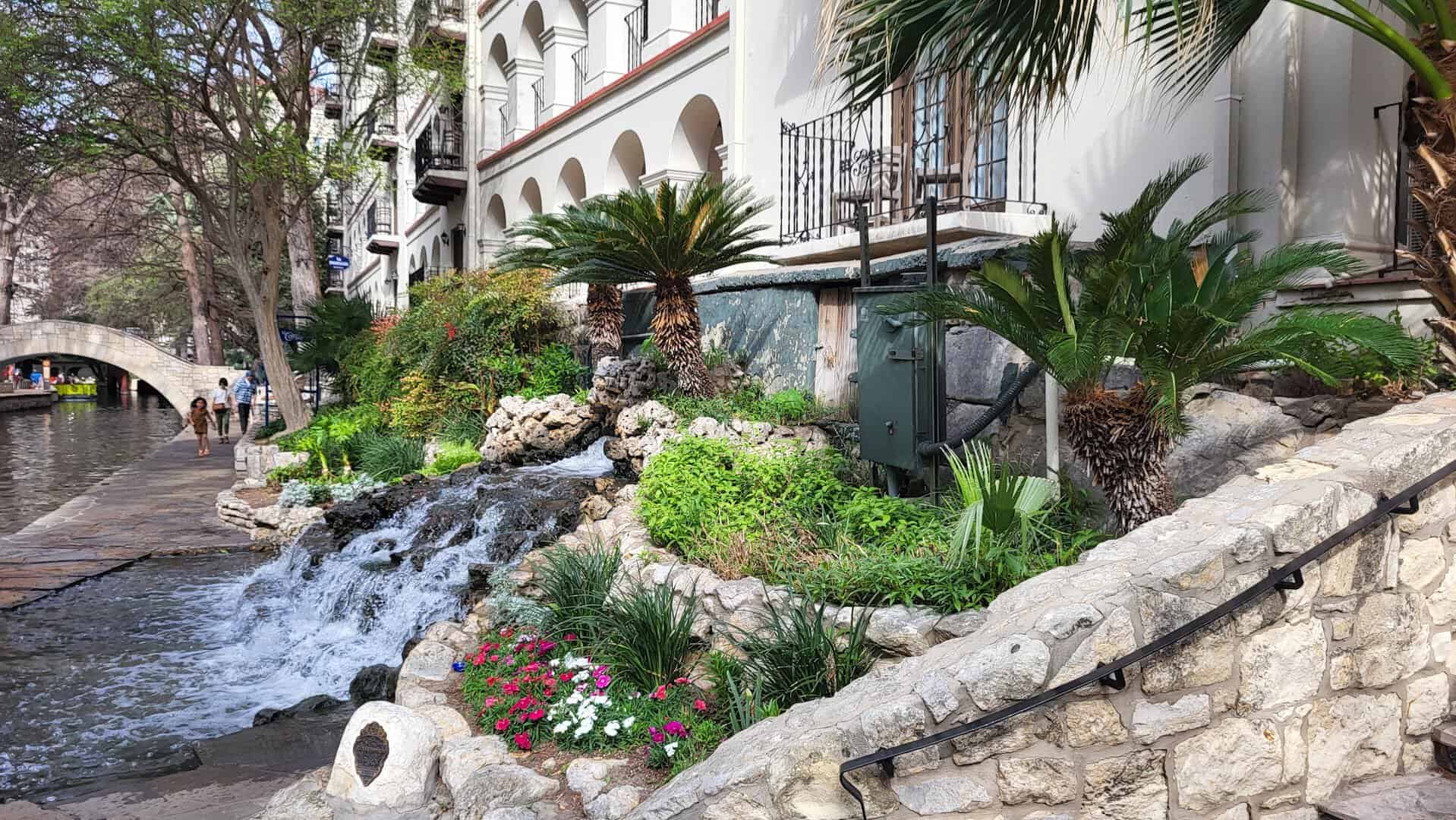 Stone banks, plants and an arched footbridge on the San Antonio River Walk in Texas