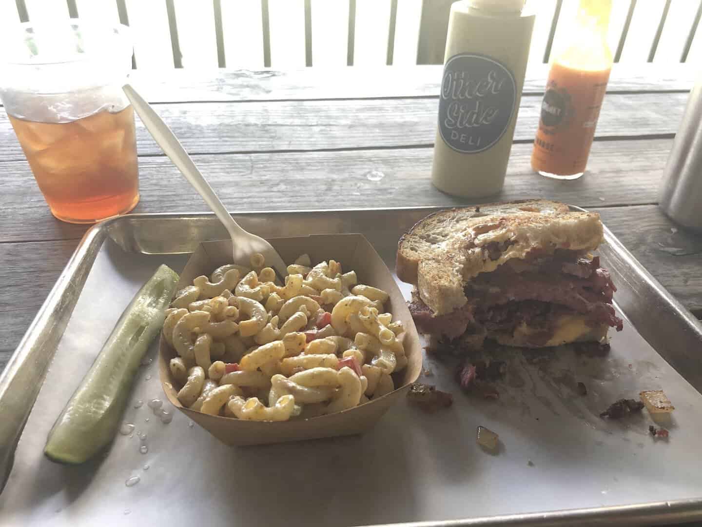 Deli sandwich with mac salad and drinks on a tray at Otherside Deli in Austin