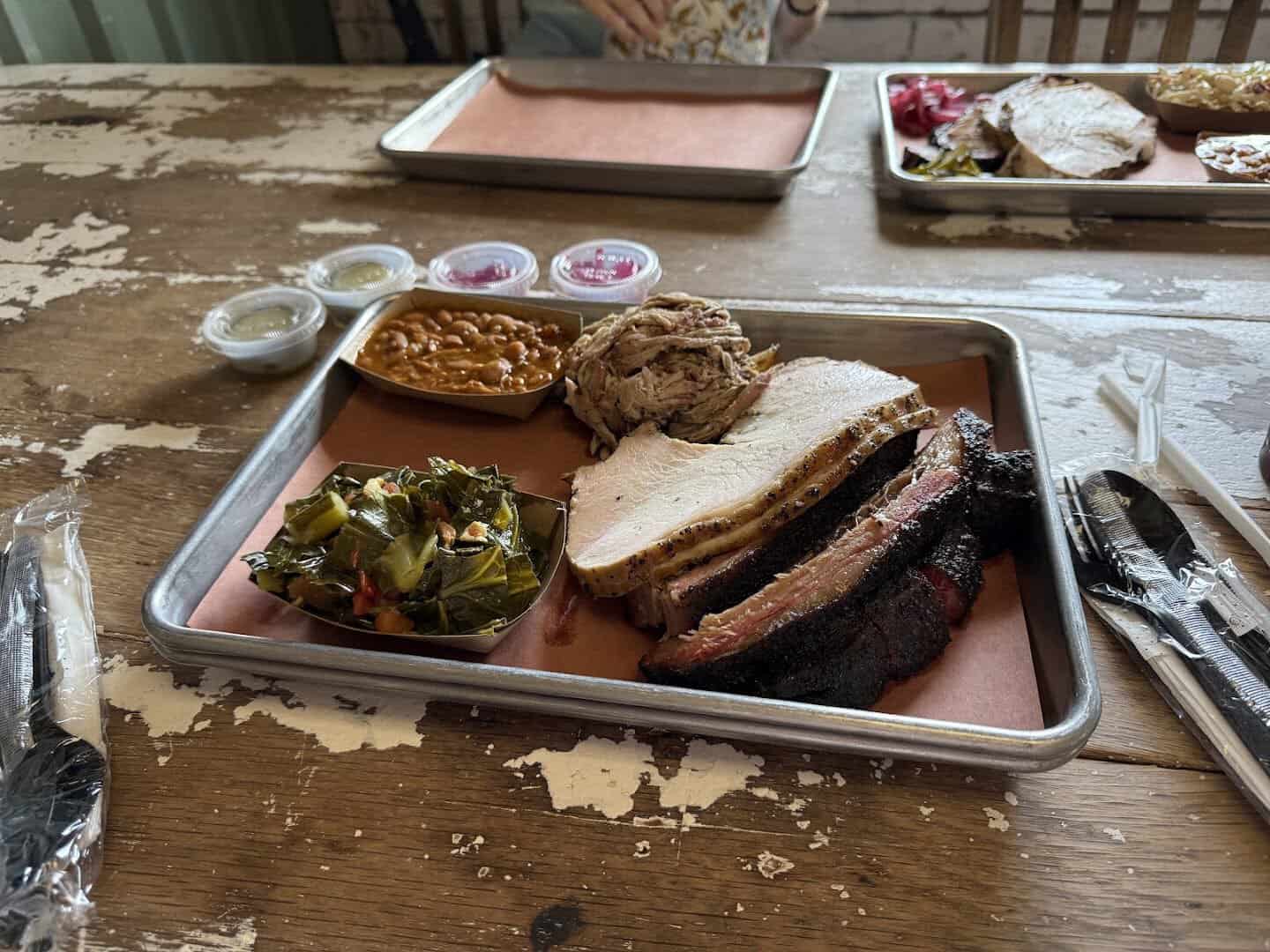 Sliced smoked brisket, sausage and sides on a tray at Truth Barbeque in Brenham, Texas