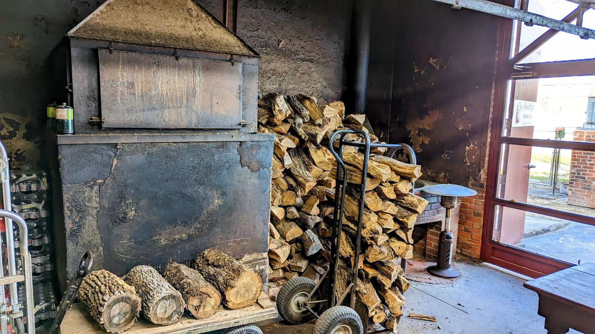 Brick smoke pit stacked with post oak firewood at Smitty's Market in Lockhart, Texas
