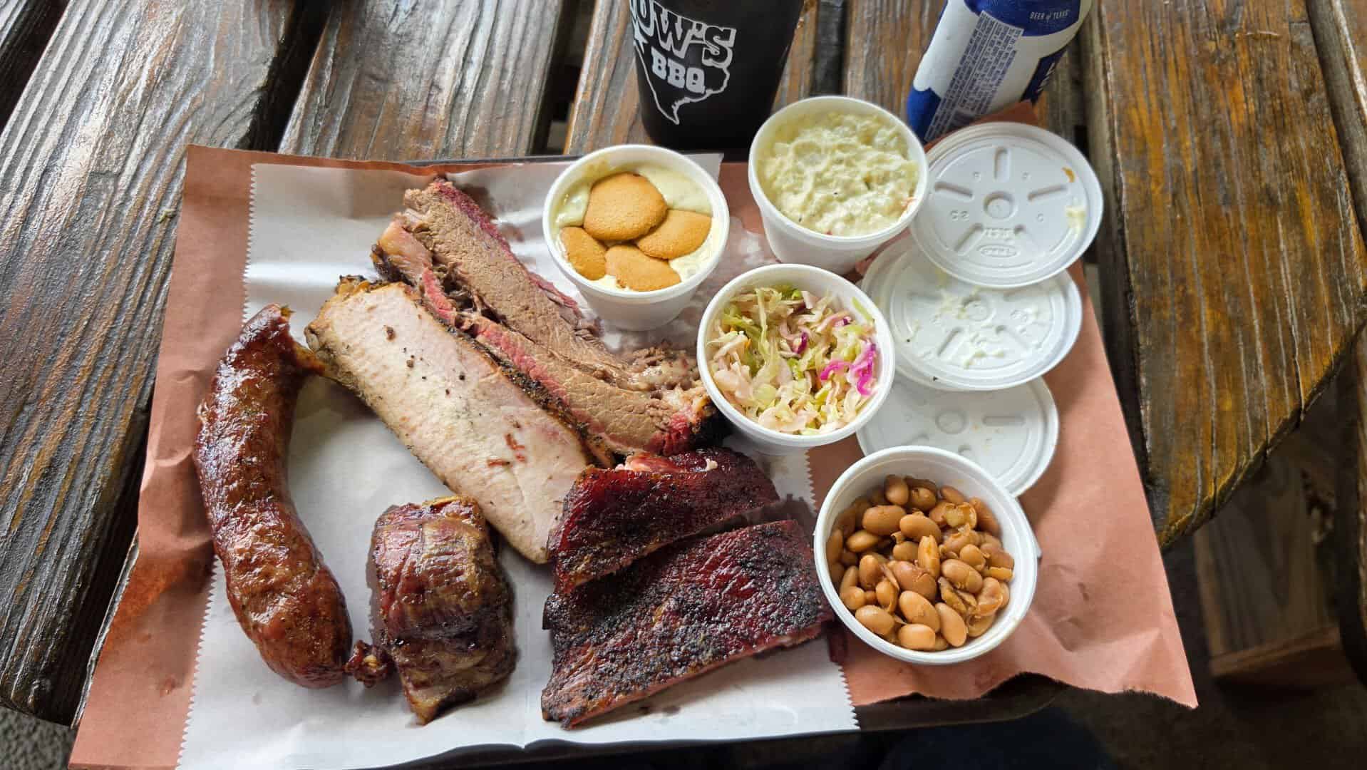 Plate of brisket, sausage and pork ribs with sides at Snow's BBQ in Lexington, Texas