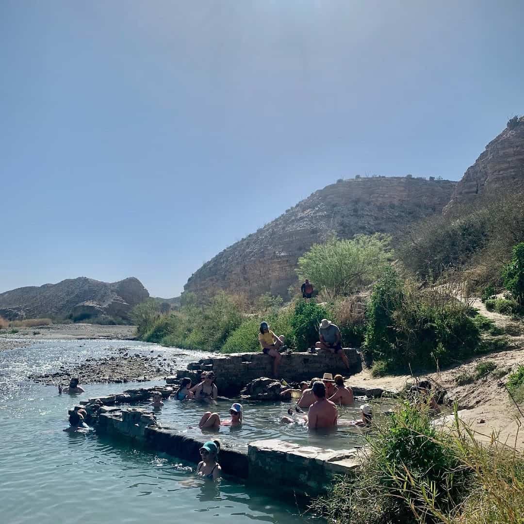 Soaking in the warm mineral pool with desert mountains behind at Big Bend Hot Springs