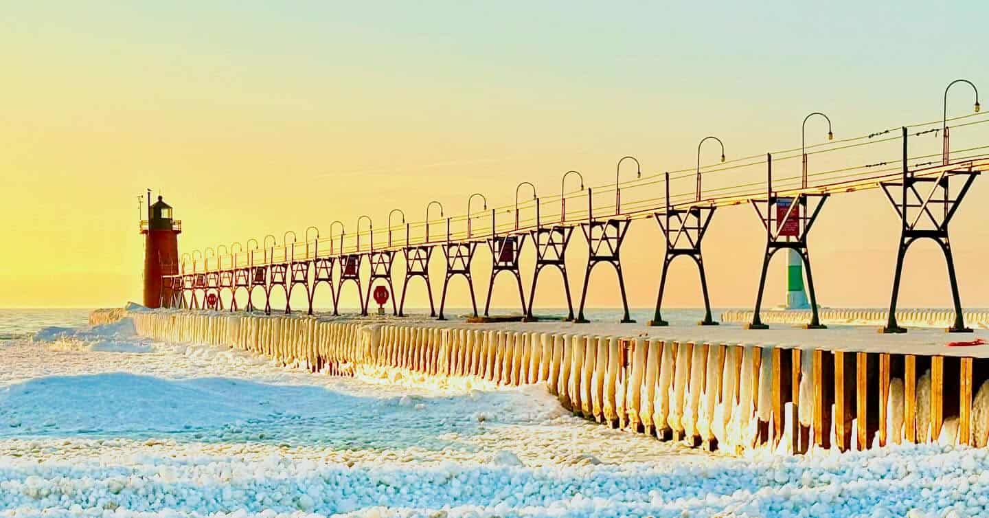 The red South Haven South Pier Lighthouse and catwalk at sunset in South Haven, Michigan