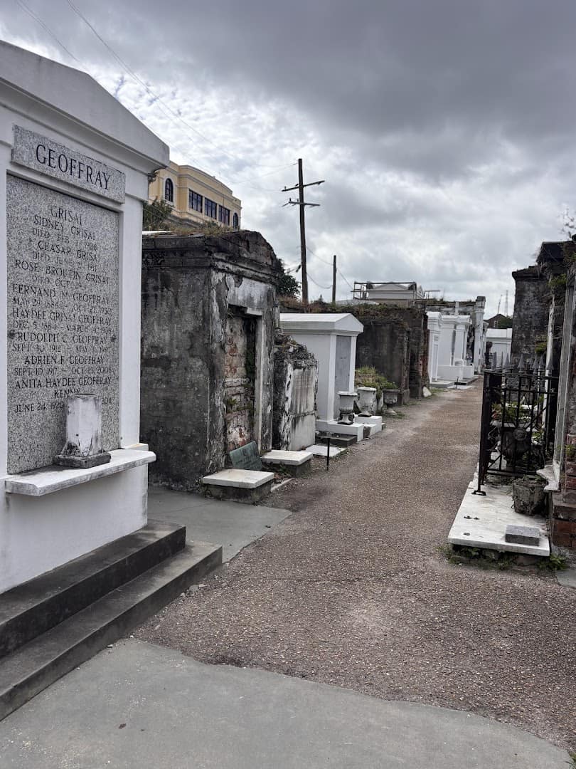 Rows of whitewashed above-ground tombs along a path at St. Louis Cemetery No. 1 in New Orleans, Louisiana