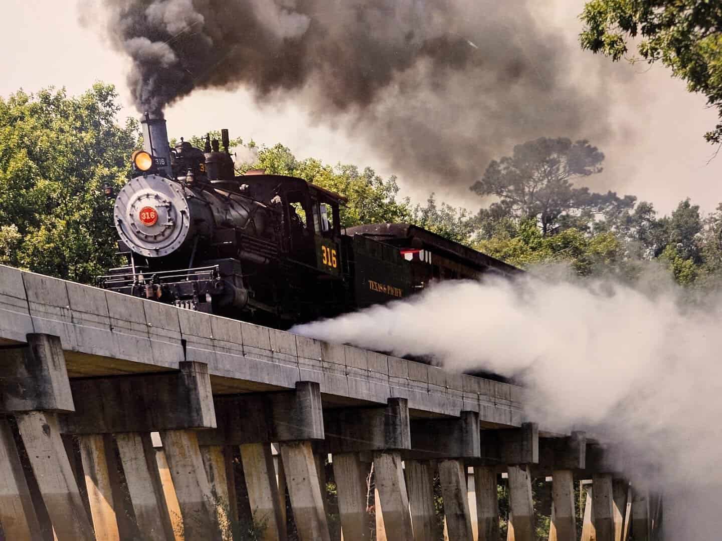 Steam locomotive crossing a timber trestle bridge on the Texas State Railroad