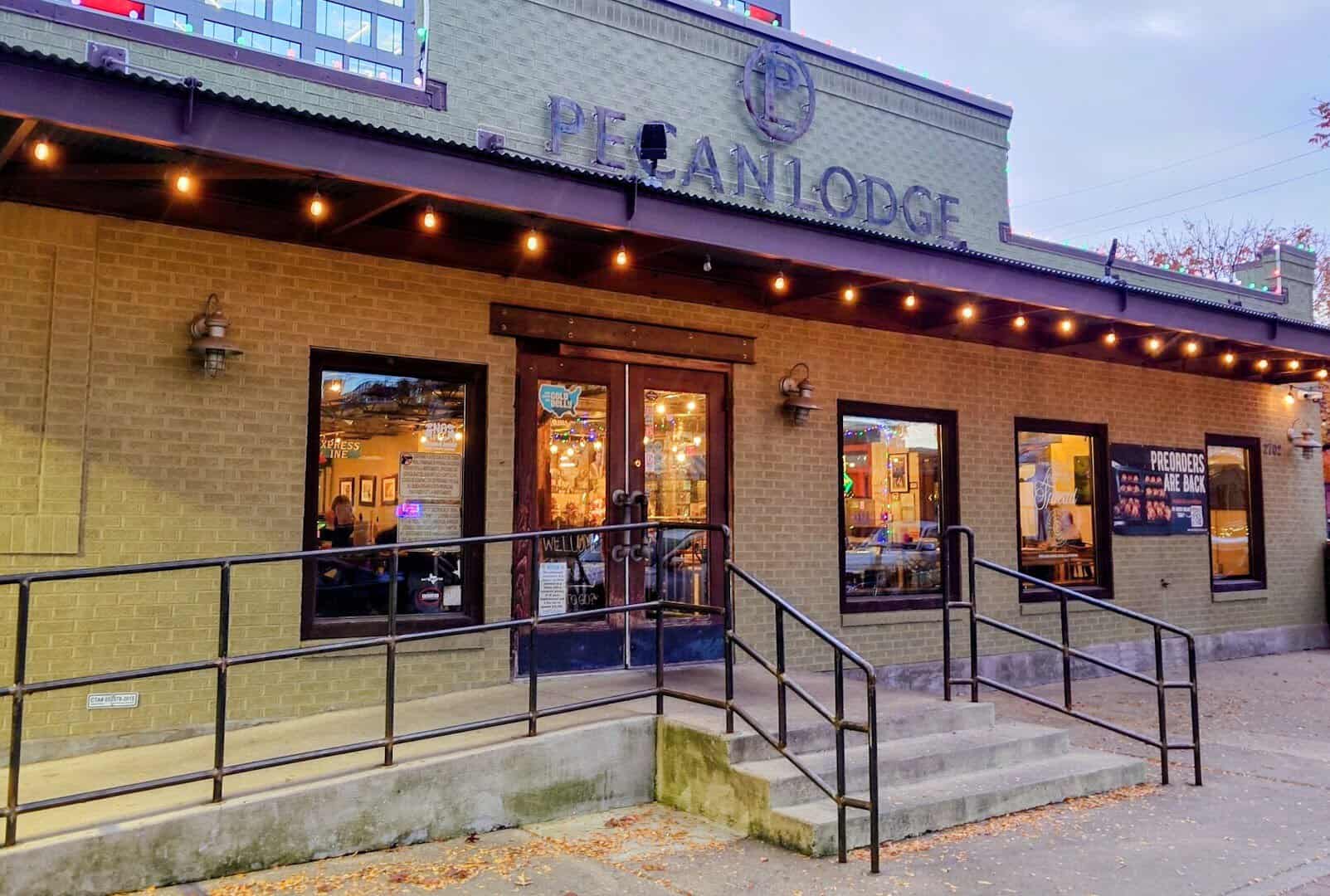 The lit Pecan Lodge storefront sign at dusk in Deep Ellum, Dallas