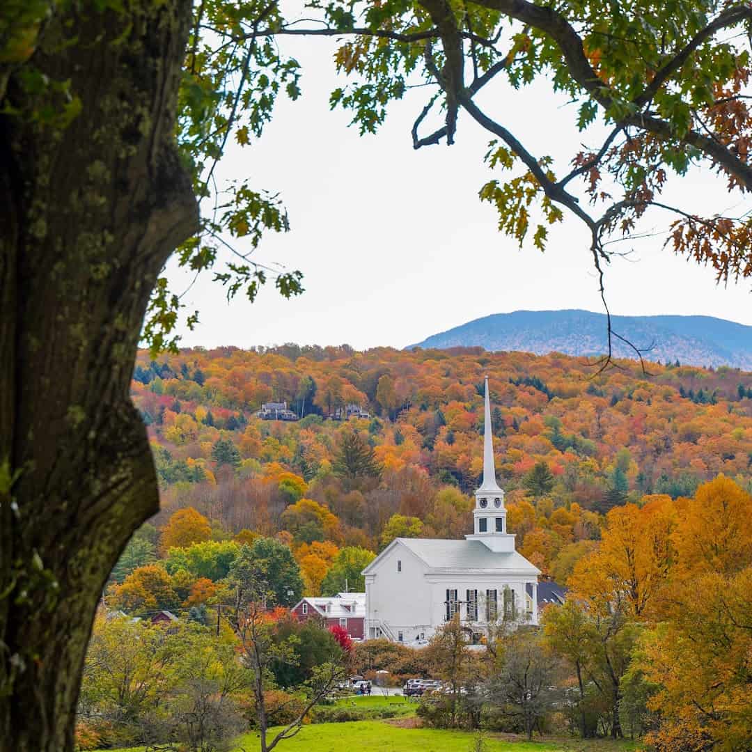 White church steeple framed by autumn mountains in Stowe, Vermont