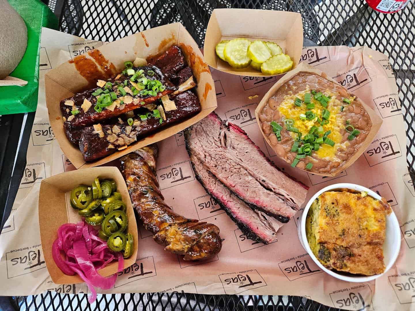 Sliced brisket, pork ribs and sides in paper boats at Tejas Chocolate and Barbecue in Tomball, Texas