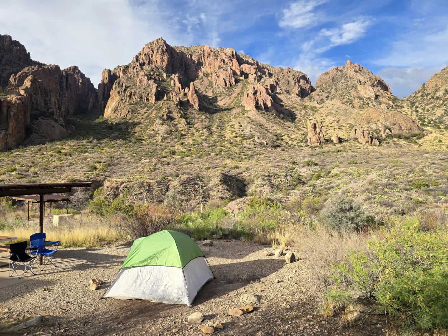Tent pitched beside a shade shelter at Chisos Basin Campground below the rocky basin rim
