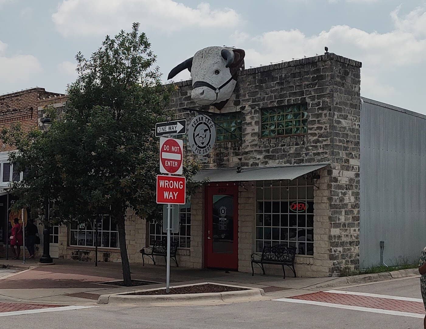 Corner storefront of Texan Cafe and Pie Shop with its steer sign and red door in downtown Hutto, Texas