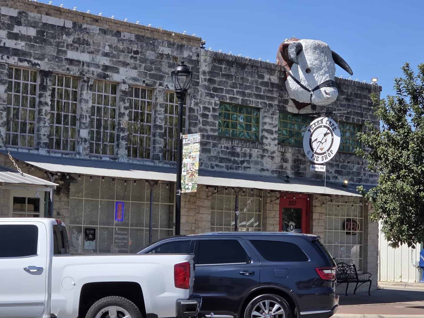 Stone storefront of Texan Cafe and Pie Shop with a hippo figure on the roof in Hutto, Texas